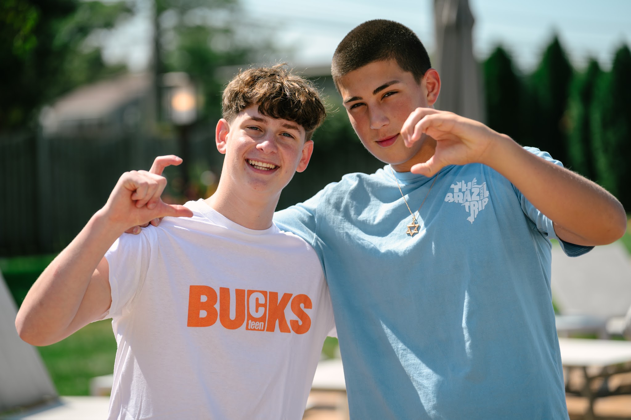 Two CTeen Bucks teens pointing at the Bucks Teen logo on their shirts